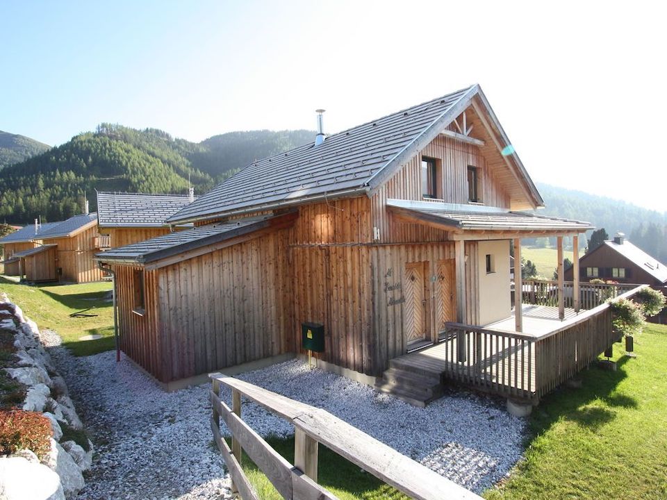 Holzhaus zwischen Bergen, Sonne strahlt