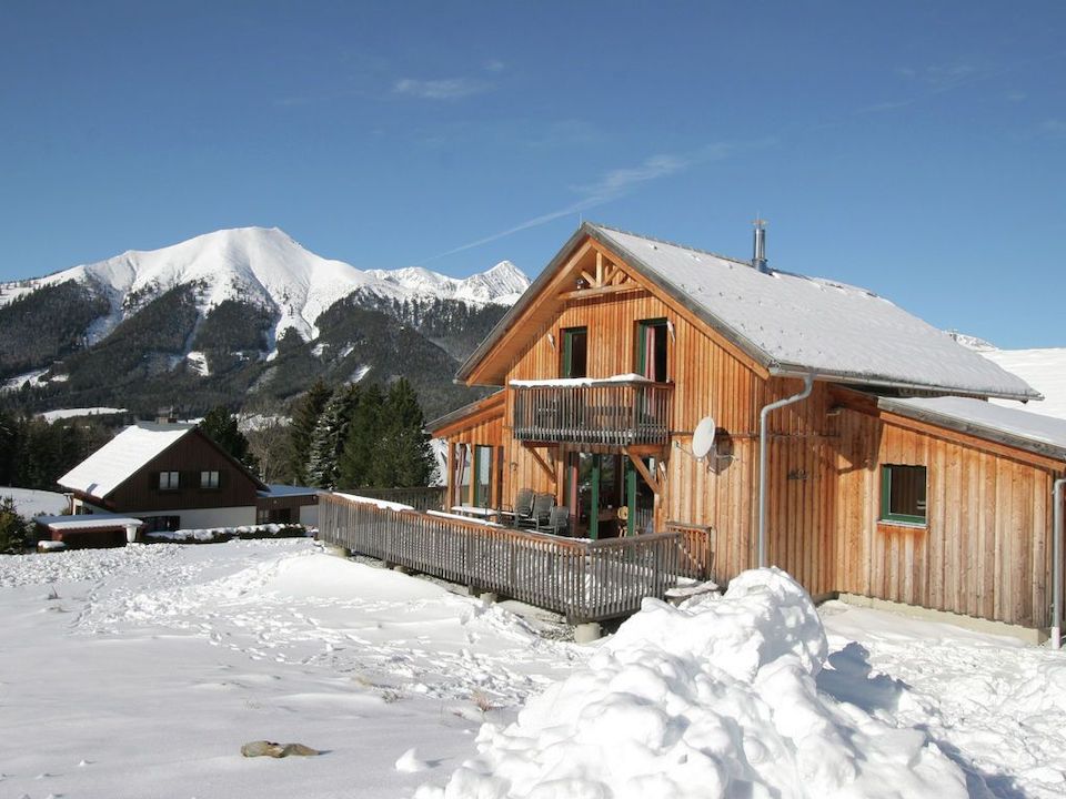 Holzhaus mit Schnee bedeckt, Berge im  Hintergrund